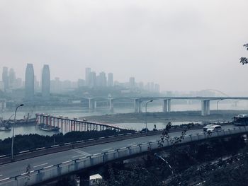 Bridge over river in city against sky