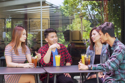 Friends talking while having juices at table