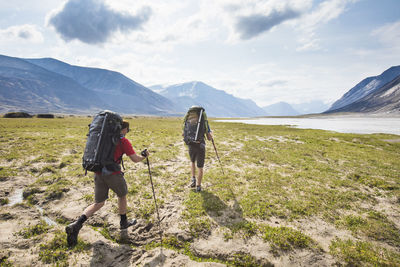 Rear view of backpackers hike over arctic tundra in akshayak pass