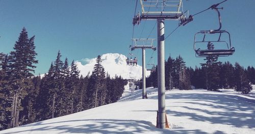 Ski lift over snow covered mountains against sky