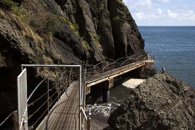 Bridge by rock formations against sea