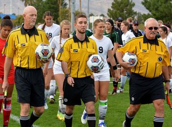 Full length of friends standing on soccer field