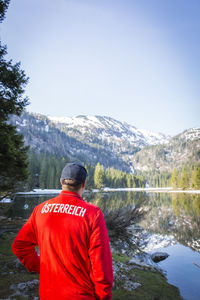 Rear view of man standing by mountain against sky