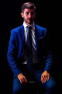 Businessman sitting on chair against black background