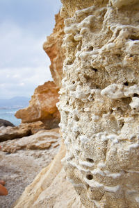Close-up of rock formation on beach against sky