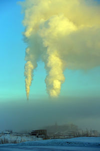 Smoke emitting from chimney against sky