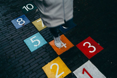 Low section of person playing hopscotch on street