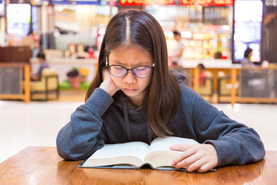 Close-up of girl reading book at library