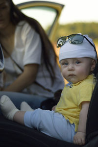 Portrait of cute baby boy sitting by mother