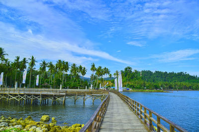 Pier amidst trees against blue sky