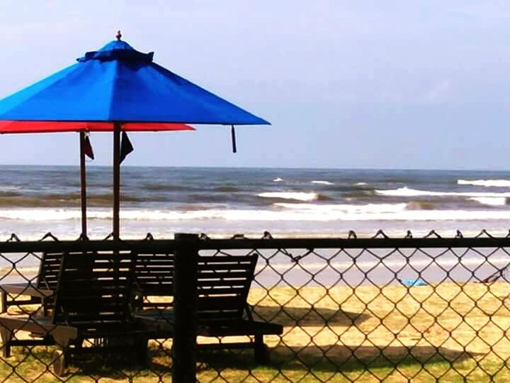 DECK CHAIRS ON BEACH AGAINST SKY