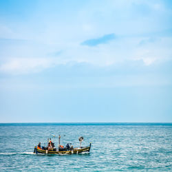 Fishermen on boat in sea against sky