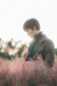 Man by plants against clear sky