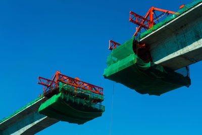 Low angle view of crane against clear blue sky