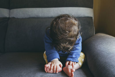 Rear view of boy sitting on sofa at home