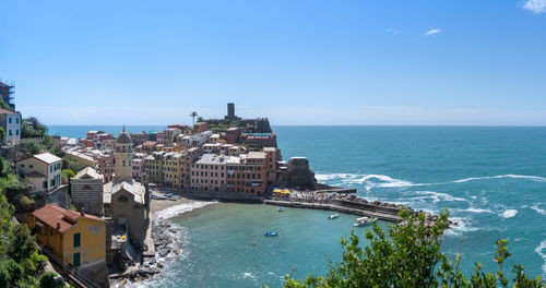 Buildings by sea against blue sky