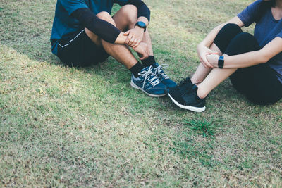 Low section of couple sitting on grassy field