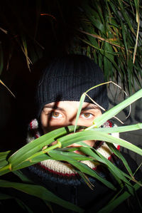 Portrait of young woman standing by plants outdoors