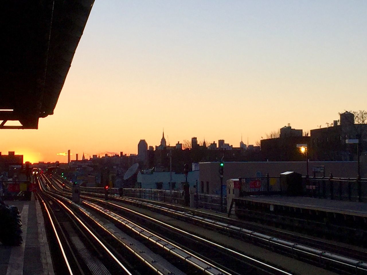 TRAIN AT RAILROAD STATION AGAINST CLEAR SKY AT SUNSET