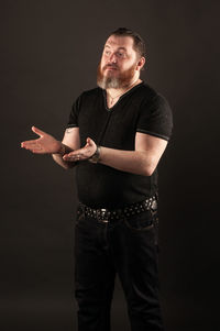 Full length portrait of young man standing against black background