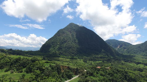 Scenic view of green mountain against cloudy sky