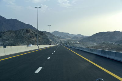 Empty road by mountain against sky