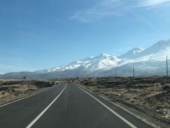 Road by mountains against clear blue sky