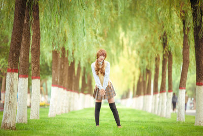 Full length of woman standing against trees at park