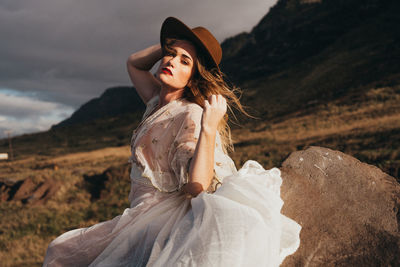 Portrait of beautiful woman wearing hat while standing against sky