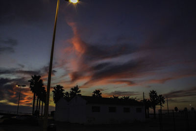 Silhouette trees and buildings against sky at sunset