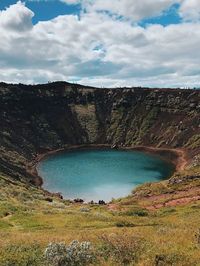 Scenic view of lake amidst mountain against cloudy sky