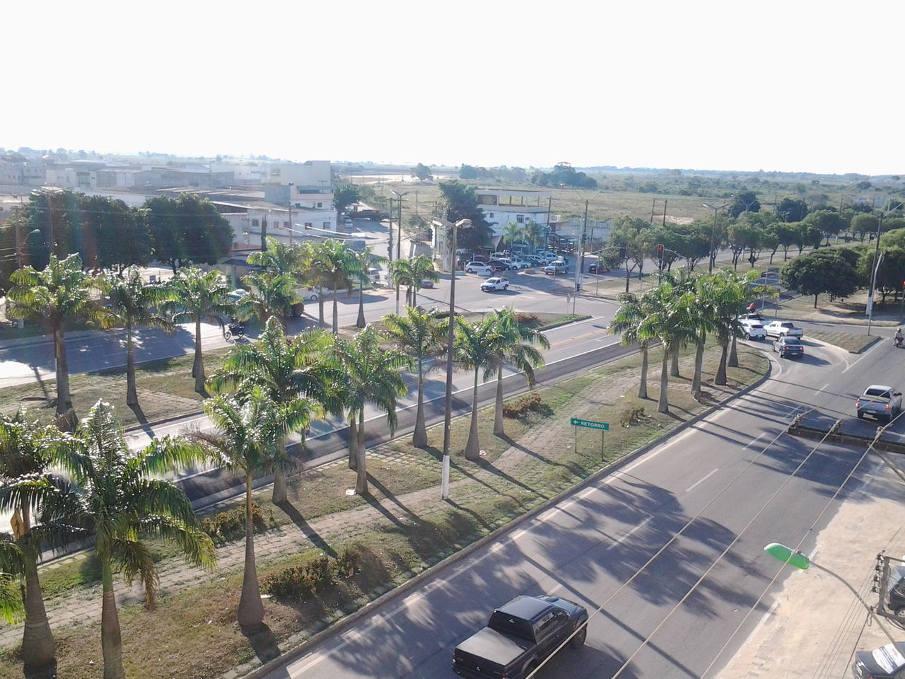 transportation, tree, building exterior, car, built structure, architecture, road, land vehicle, city, street, clear sky, high angle view, mode of transport, palm tree, road marking, incidental people, day, city street, outdoors, growth