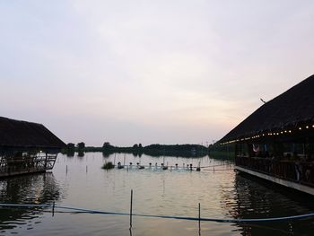 Scenic view of lake by buildings against sky during sunset