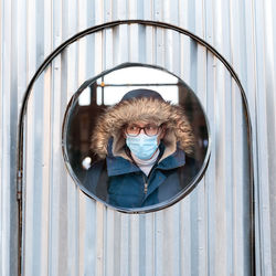 Man wearing mask looking through window