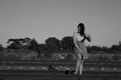 Full length of woman standing on railroad track against sky