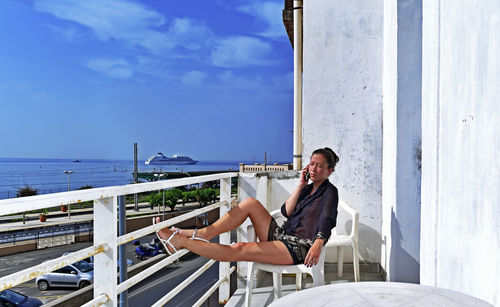 Mid adult woman sitting in balcony during sunny day