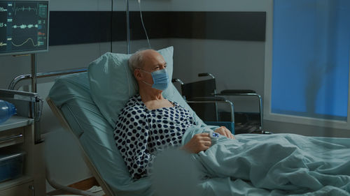 Side view of woman using mobile phone while sitting on bed at home