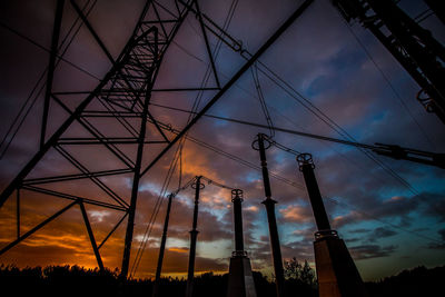 Low angle view of electricity pylon against dramatic sky