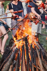 Close-up of people grilling food on bonfire