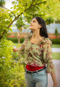 Young woman standing against plants
