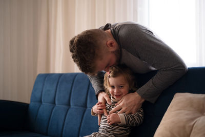 Father playing with daughter at home
