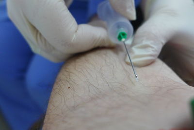 Close-up of doctor injecting syringe in patient arm