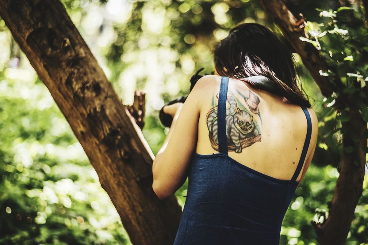 tree, one person, plant, real people, focus on foreground, tree trunk, trunk, young adult, lifestyles, leisure activity, women, adult, three quarter length, rear view, day, nature, young women, forest, land, hairstyle, outdoors