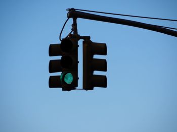 Low angle view of road sign against clear blue sky