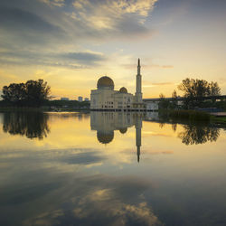 Reflection of church in lake against sky during sunset