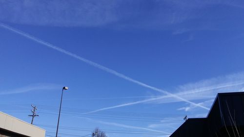 Low angle view of vapor trail against blue sky