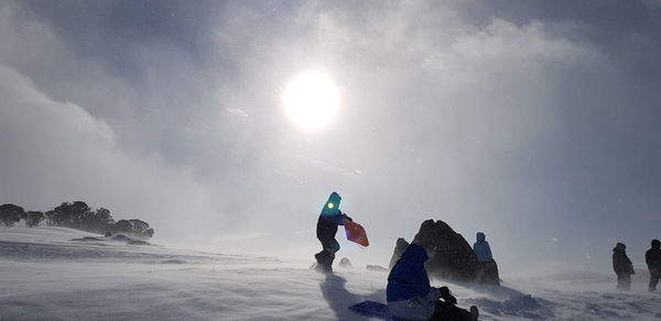 People on snowcapped mountain against sky