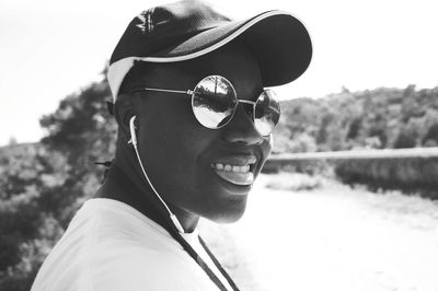 Young man wearing sunglasses listening music against sky