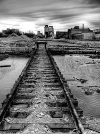 Railroad tracks by water against sky