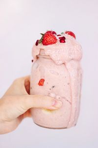 Close-up of woman holding strawberry over white background